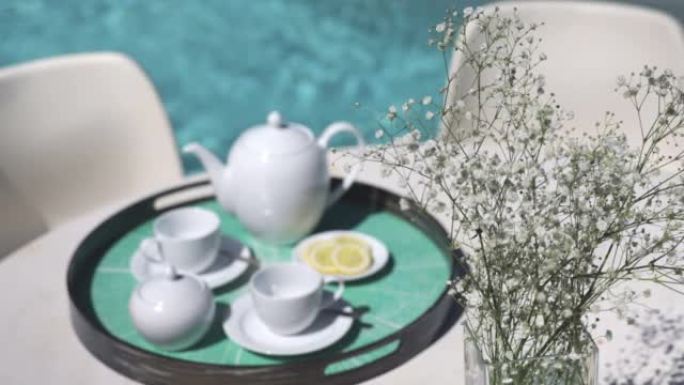 阳光明媚宁静的池畔餐桌上的茶水服务
