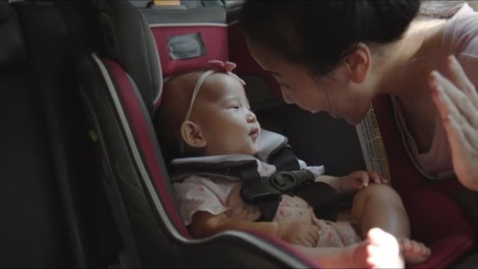 亚洲妈妈和婴儿坐在汽车座椅上玩耍，为家庭公路旅行做准备。快乐的幼儿练习安全的汽车旅行。乘客安全产品概