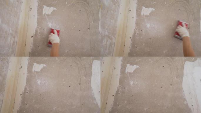 用砂纸擦墙。一只手在墙上摩擦的特写镜头