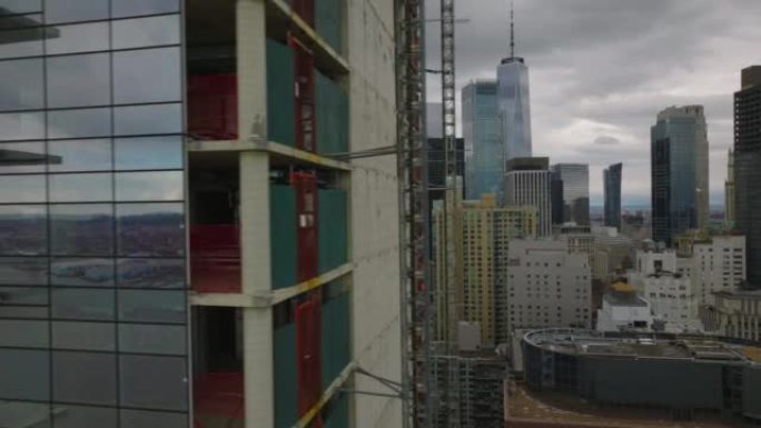 玻璃立面新型现代高层建筑施工现场滑动展示。市中心的摩天大楼在背景阴云密布的天空下。美国纽约市曼哈顿