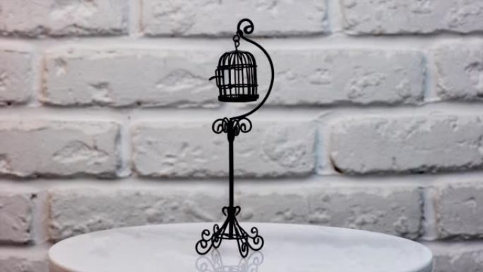 旋转桌子上金丝雀的小黑笼。精美的玩具鸟笼，用于玩偶之家的装饰。特写。