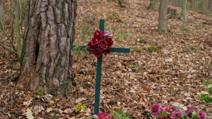 森林中被忽视的匿名坟墓上的金属十字架