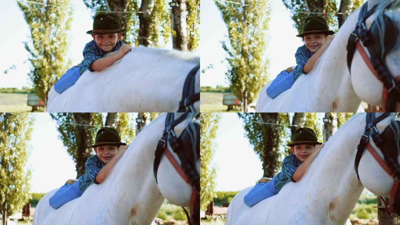 一个微笑的小男孩的肖像，帽子躺在马背上，看着相机