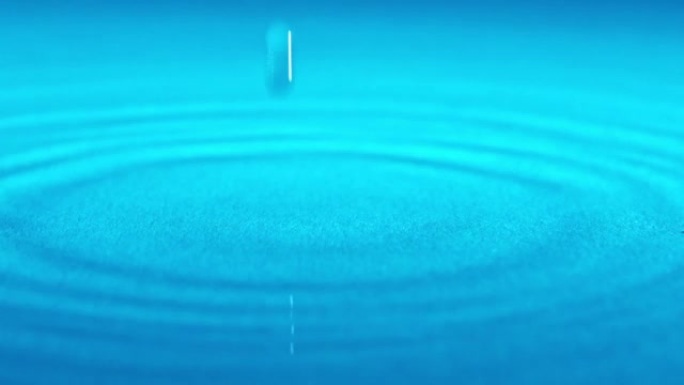 慢动作水滴落在蓝色背景的表面上