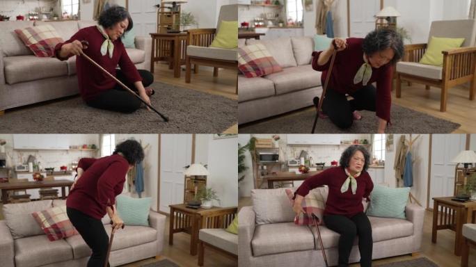 亚洲退休奶奶摔倒在家里的客厅地板上后挣扎着用棍子站起来的快进镜头。她坐在沙发上休息时靠在枕头上
