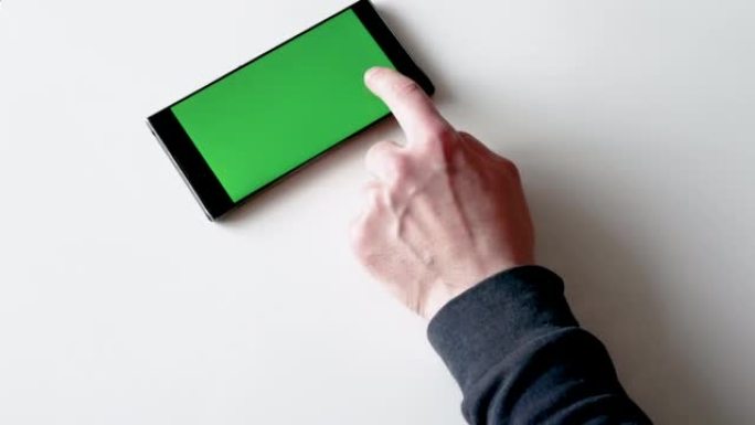 一名男子使用带有绿色显示屏的智能手机。在彩色钥匙智能手机屏幕或绿屏智能手机上滑动手指以复制空间