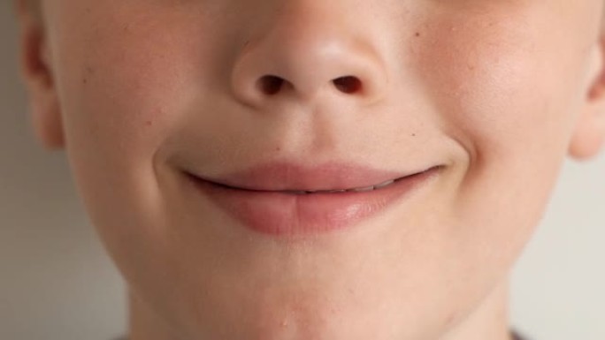 高加索儿童鼻子和嘴巴的特写。微笑，然后舔嘴唇，露出牙齿。白色牙齿之间的间隙。孤立在白色背景上