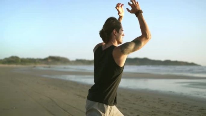 健康男子在沙滩上锻炼，练习气功，太极拳瑜伽。
