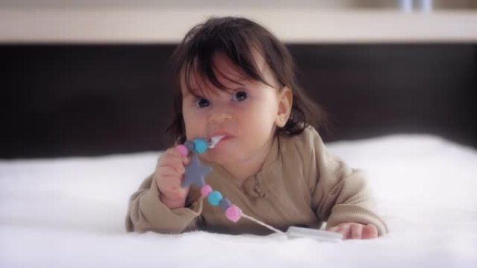 婴儿趴在育婴室的床上，舔着奶嘴托。