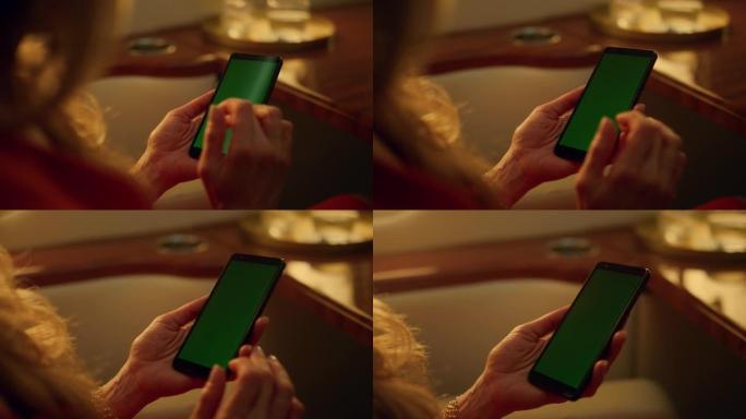 女士在公司旅行特写中使用绿色智能手机。手动滚动模型屏幕