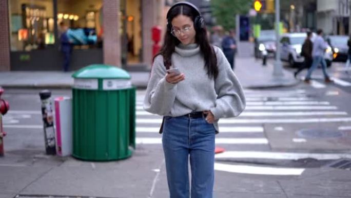 穿着休闲装的无忧无虑的女游客在城市周围漫步，用手机设备聊天，用流行的播客使用音乐应用程序
