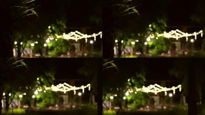 晚上在公园灯光场的晚宴在花园悬挂模糊拍摄