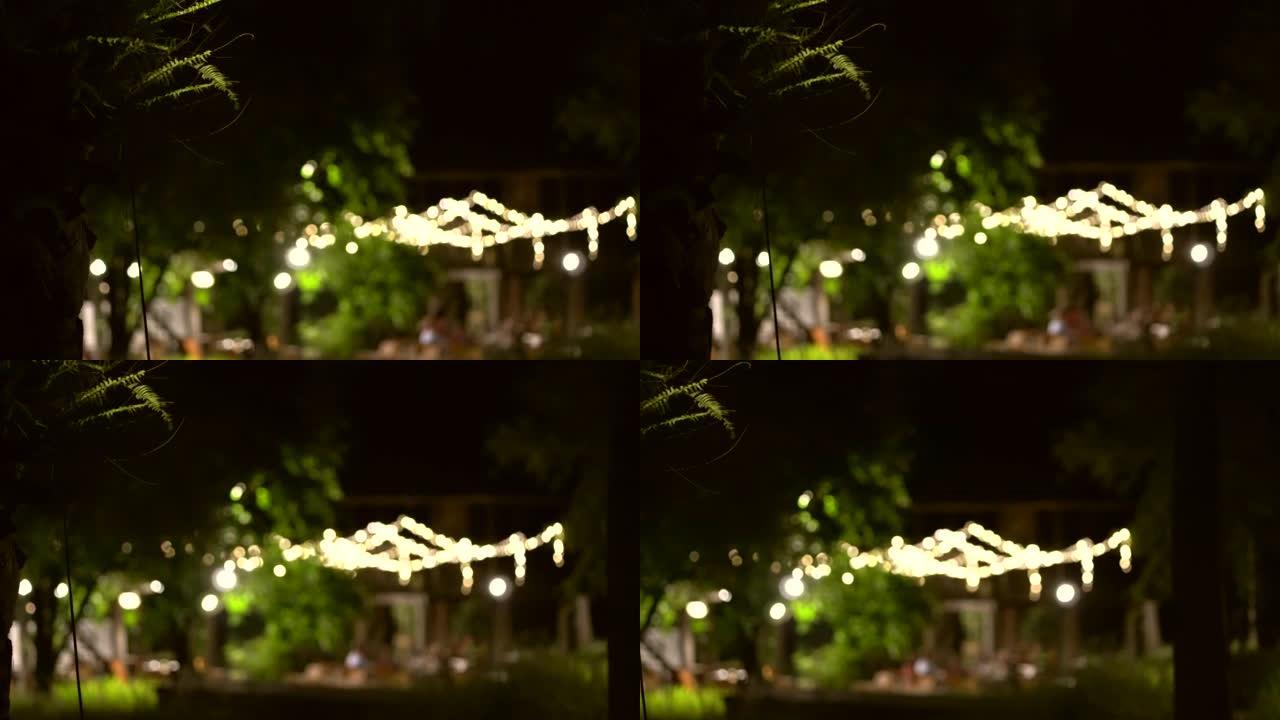 晚上在公园灯光场的晚宴在花园悬挂模糊拍摄