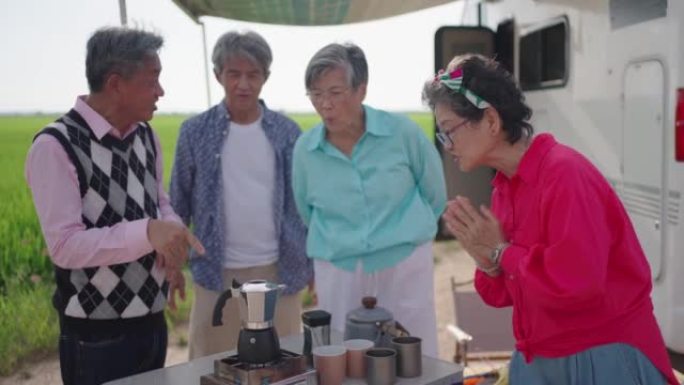 亚洲华裔资深朋友早上在稻田的露营车旁等待咖啡沸腾