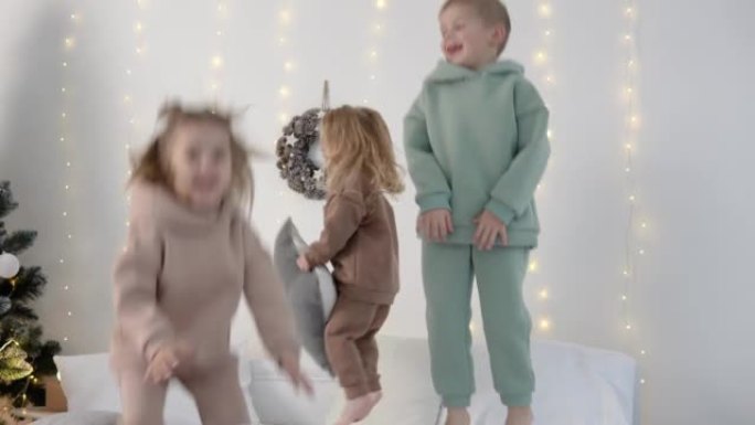 孩子们在床上跳来跳去，枕头靠近圣诞节装饰品