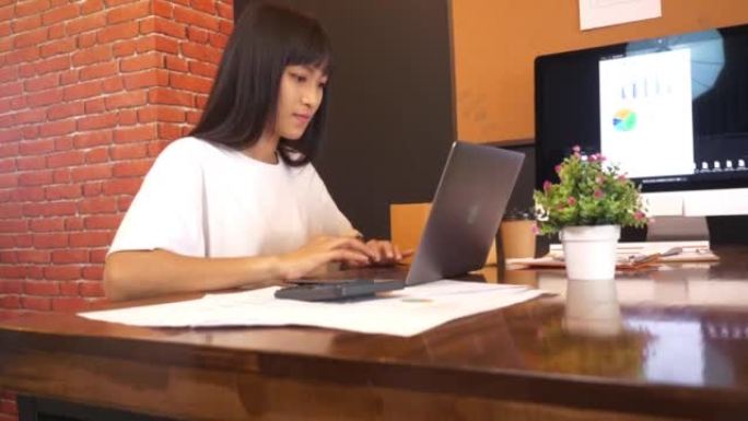 自由职业者年轻的亚洲女商人休闲装使用笔记本电脑在家工作。