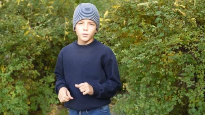 儿童博客作者在公园录制他的视频vlog。这个男孩在户外秋天在他的博客频道的摄像机前讲话。小影响者激励