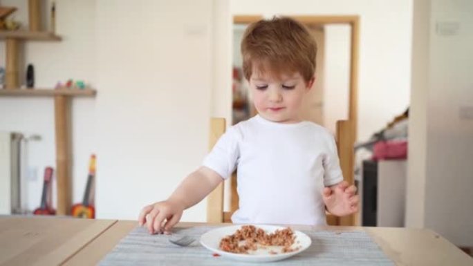 独立的高加索蹒跚学步的男孩自己吃健康的饭菜