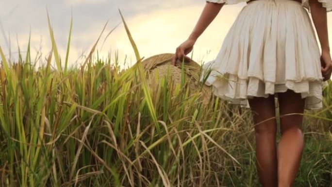 无忧无虑的女人戴着草帽走在稻田里
