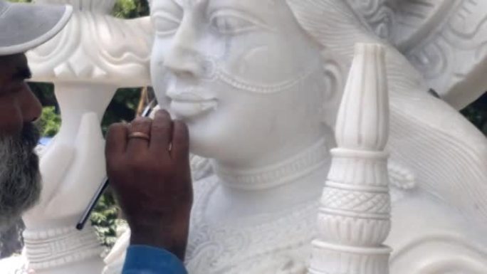 印度工匠雕刻传统印度教女神拉克希米或拉克西米白色大理石石雕或雕像出售，使用锤子和凿子，手工移动。