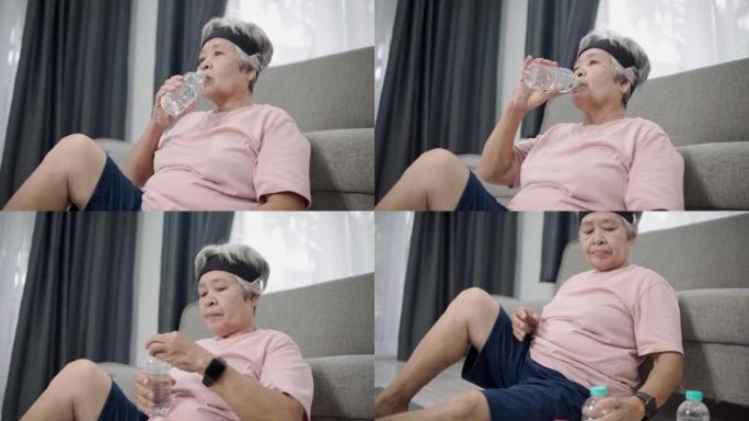 家庭锻炼理念，亚洲老年妇女在客厅锻炼后喝水。