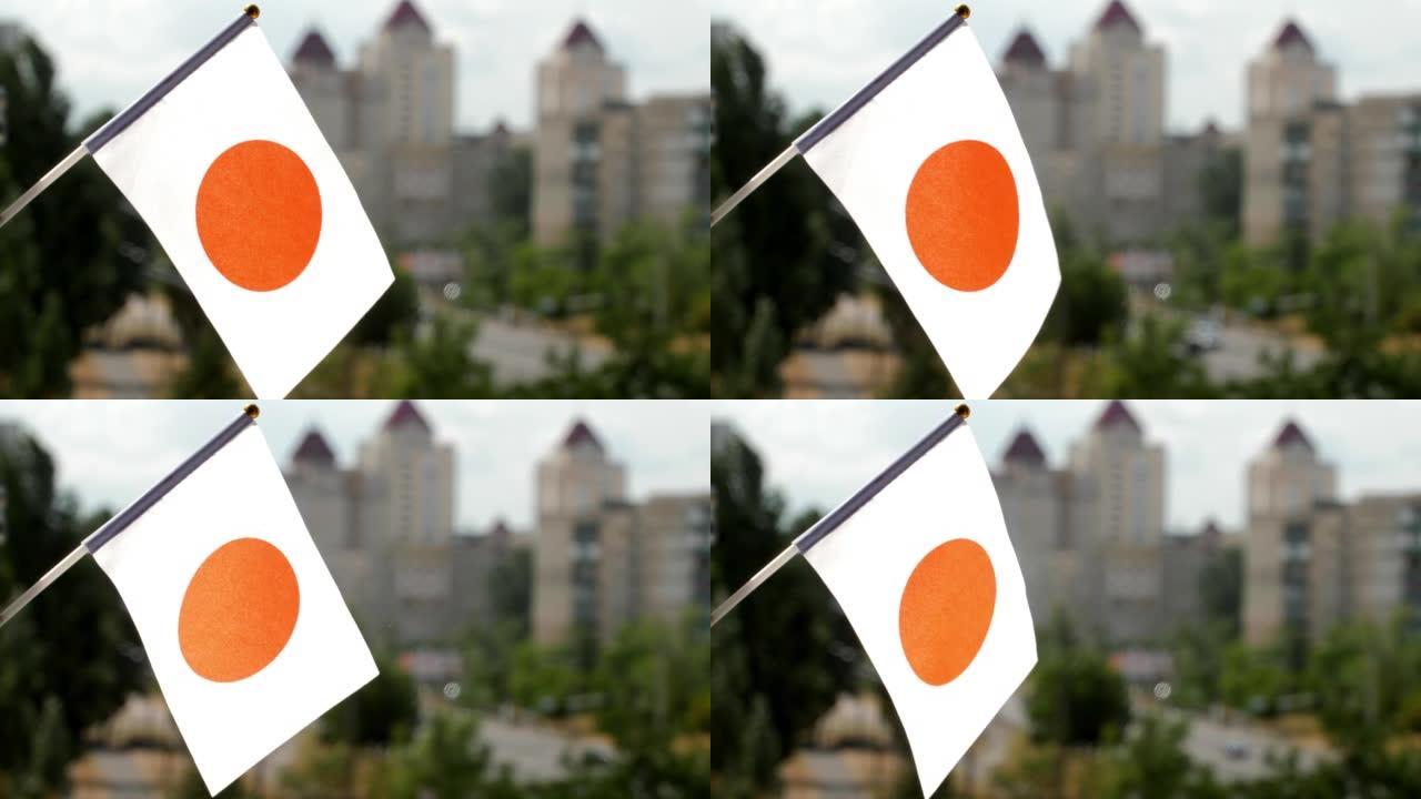 蓝天和城市街道映衬着日本国旗。挥舞日本国旗。日本的节日旗帜被太阳照亮。一面白色的旗帜，中央有一个深红