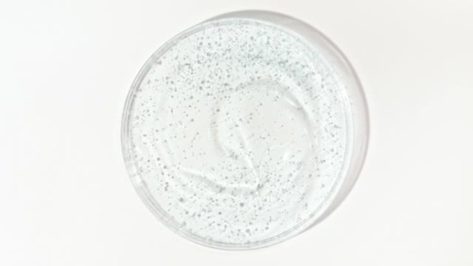 在Petri玻璃碗中带有气泡的透明蓝色化妆品凝胶液的旋转。宏丸血清、乳膏、透明质酸。有机化妆品，药品