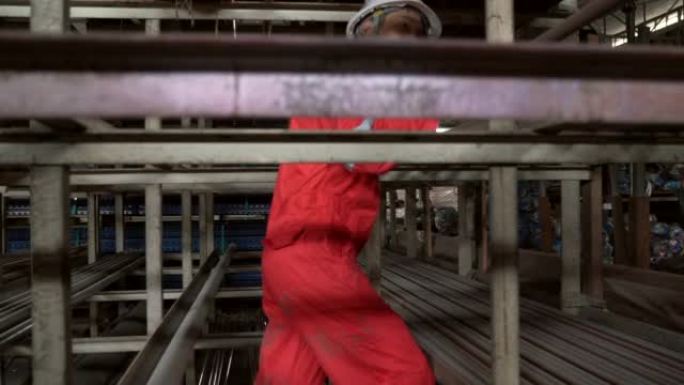 金属工业-一名亚洲工人在仓库中移动球墨铸铁管的垂直平移镜头