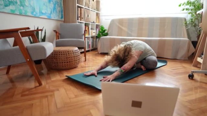 女人在笔记本电脑上进行在线瑜伽课，同时在家锻炼