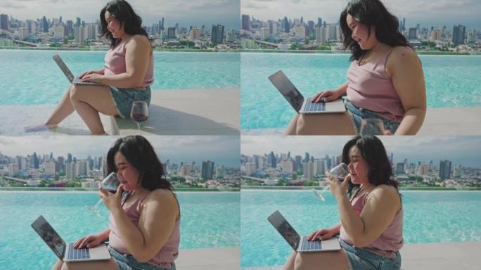 夏季，大型亚洲女性使用笔记本电脑坐在游泳池附近
