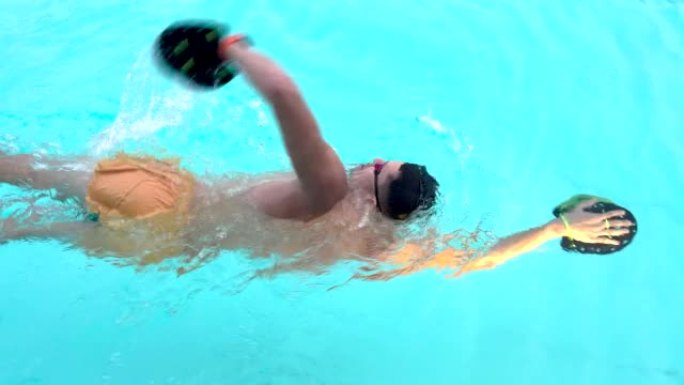游泳者。职业游泳者在游泳池为比赛做准备。戴着泳镜和疯狂波浪桨的年轻运动员迅速以自由式的方式沿着游泳池