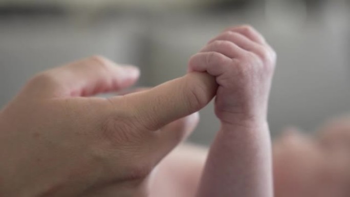新生婴儿男婴的手抓住妈妈的手指