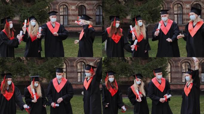 戴着防护面具的学生毕业时穿着学院服，手持文凭在镜头前摆姿势，在大学学校的欢笑背景下欢呼雀跃，获得硕士