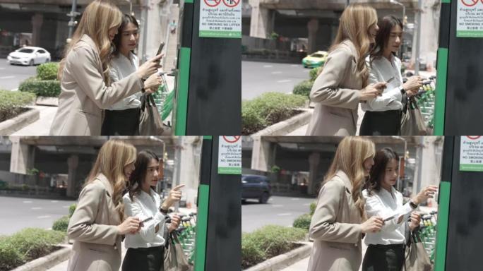 两名亚洲女商人用手机扫描二维码租自行车