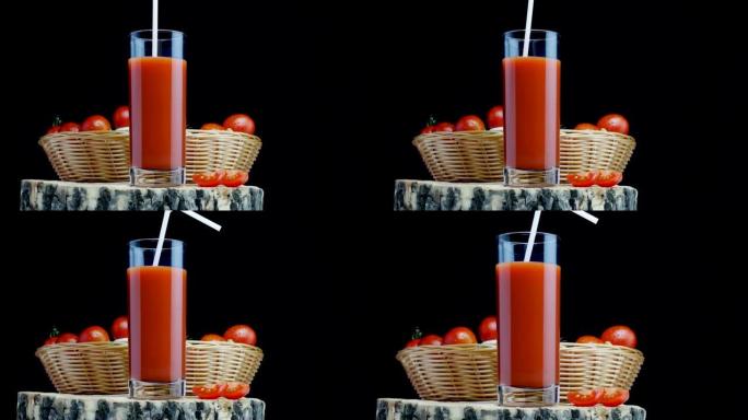 在黑色背景上的吸管玻璃杯中加入番茄鸡尾酒，在篮子中放入新鲜的西红柿，用于存放食物。番茄汁