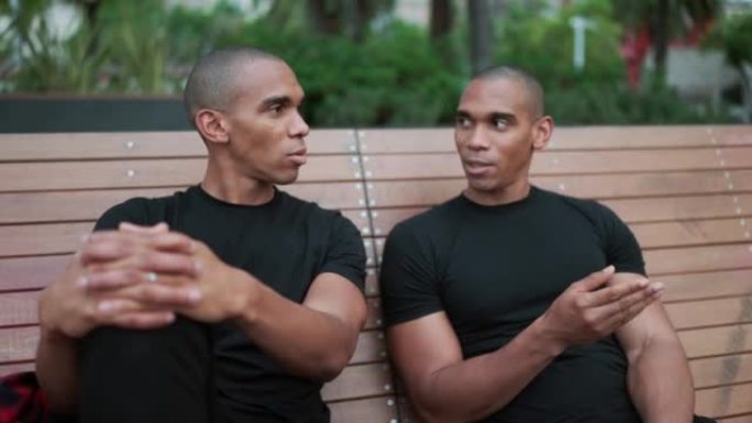 Two confident bald brothers talking while sitting 