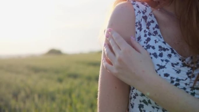在室外的绿色麦田里，雌性姜的手在她的手上抚摸手指。站在户外的红头发和雀斑的调情女孩。特写年轻女性在夏
