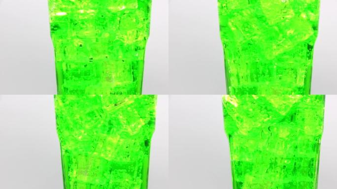 绿色苏打水，玻璃中冰。在白色背景上旋转一杯绿色苏打水饮料。