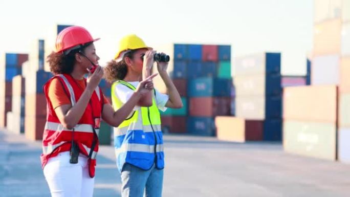慢动作双筒望远镜和对讲机。黑人女码头工人控制从仓库集装箱堆场的货物中装载集装箱箱。海运和承运人保险概