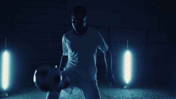 年轻的非洲裔美国人训练足球技巧，在黑暗的体育场用膝盖踢球，肖像