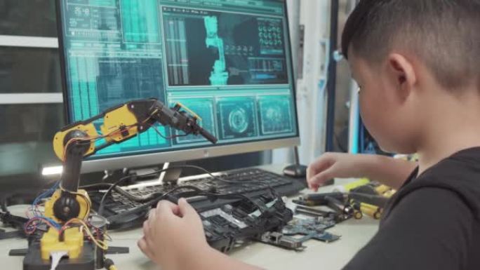 教育主题: 男孩学习如何在数字平板电脑上控制玩具机器人手臂，科学工程，教育，技术