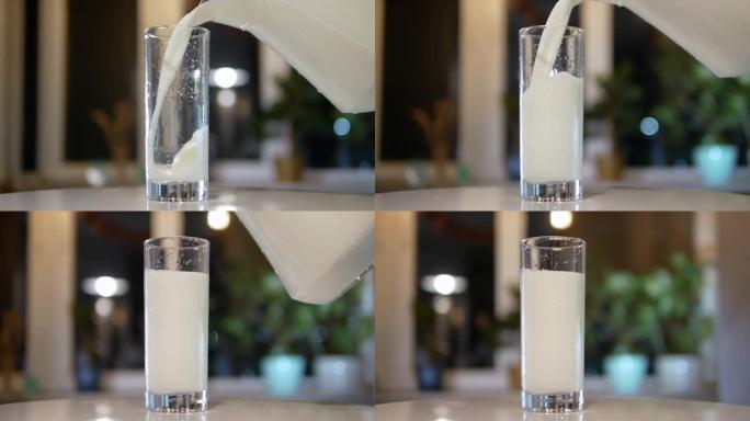 将天然牛奶从水罐倒入转盘上的玻璃杯中，将新鲜的乳制品倒入玻璃杯中，以慢动作倒入牛奶