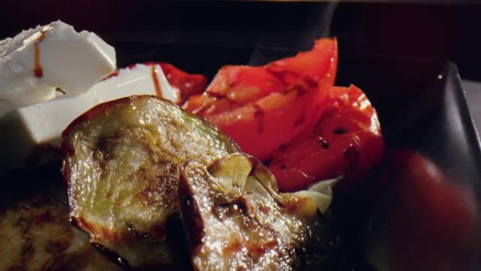 烤土豆配切成薄片的番茄，西葫芦和羊乳酪，上面覆盖着酱汁-关闭旋转