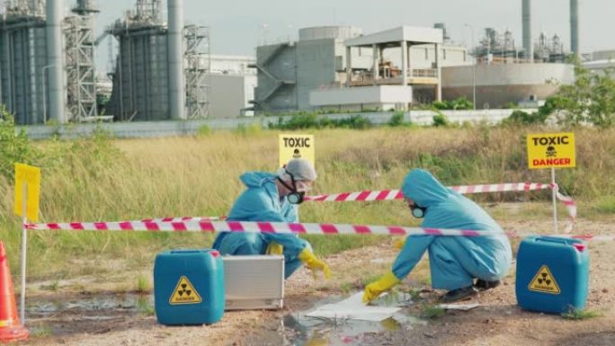 污染控制小组身穿防护服，戴着口罩，在工厂附近清理油污