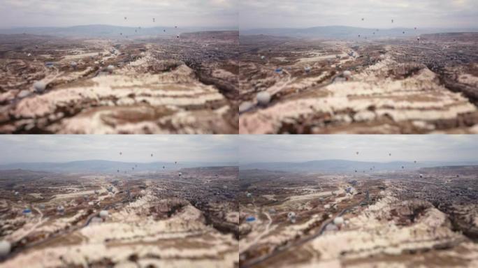 无人驾驶飞机拍摄的卡帕多细亚的岩石山谷和飞行的热气球的微缩视图