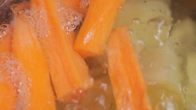 用沸水煮胡萝卜。胡萝卜和土豆，煮蔬菜汤