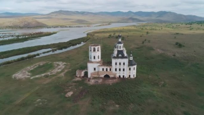 俄罗斯布里亚特共和国一座破旧教堂的鸟瞰图。被绿色草地和河流包围的教堂被毁