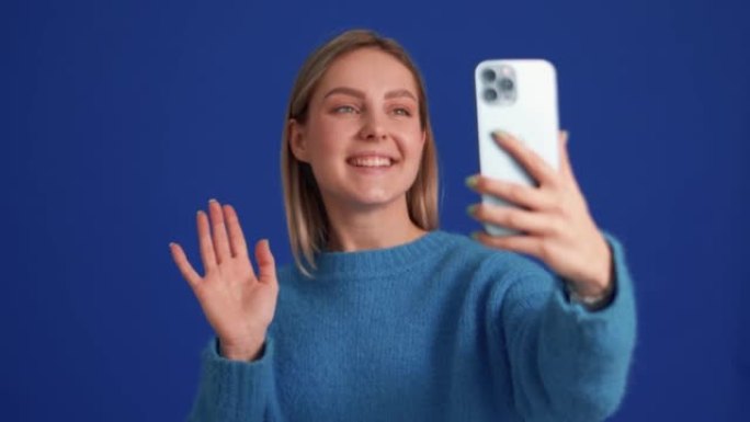 Smiling woman wearing blue sweater talking by vide