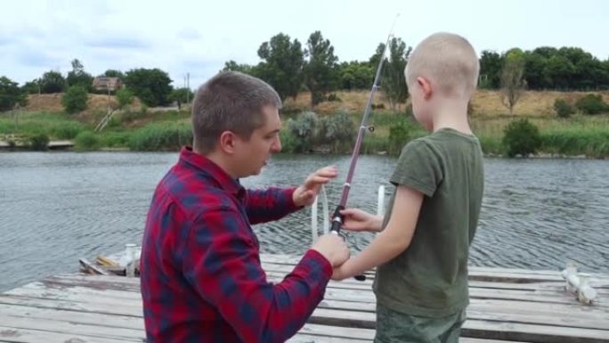 Father and son fishing. Dad shows his son how to h