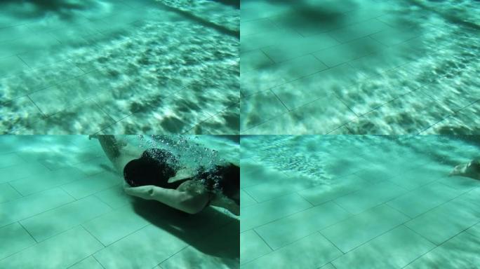 戴护目镜的女人在游泳池里水下游泳，有波浪和阴影